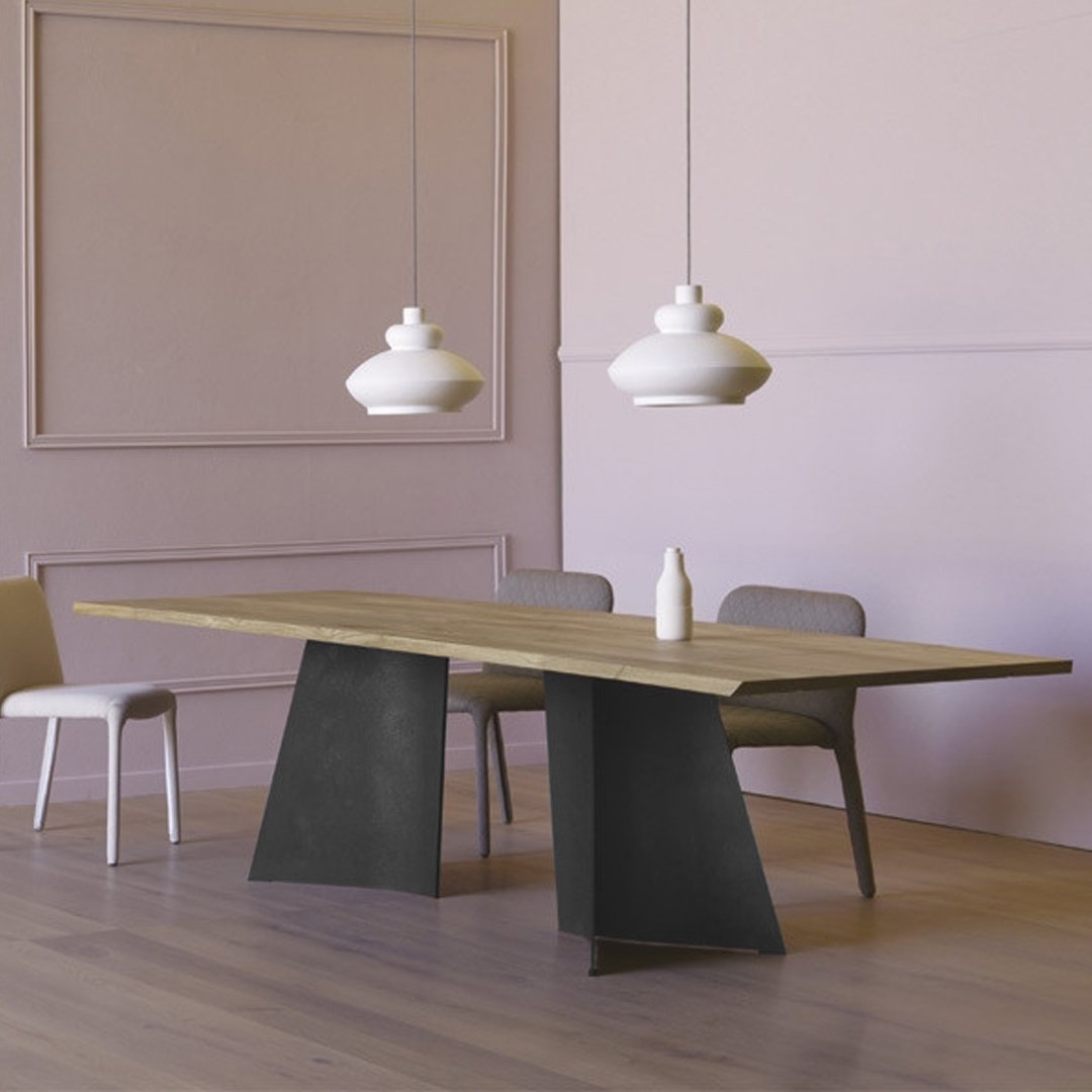 Modern wooden dining table with a light oak surface and sleek black metal legs, set against soft pastel pink walls.