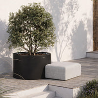 Black planter with green foliage, paired with a light gray seating option on a wooden deck. Minimalist design.