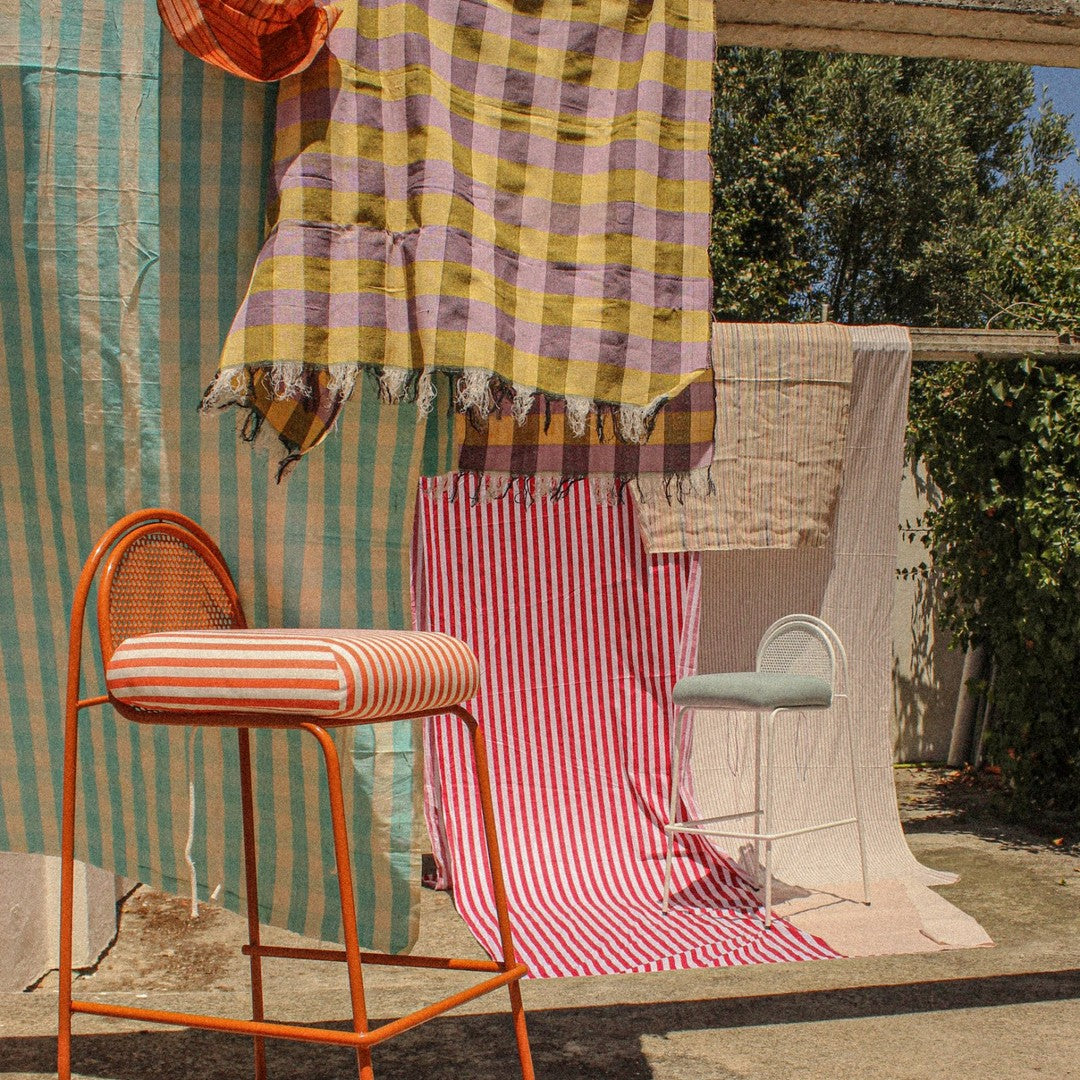 Colorful striped and checkered fabrics in varied hues of purple, orange, pink, and blue draped creatively.