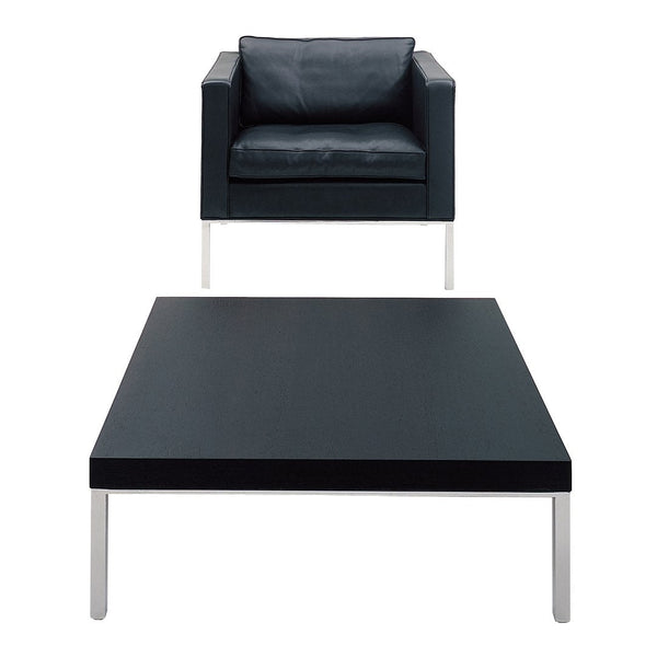 Black leather armchair and sleek black coffee table with silver legs, featuring modern minimalist design.