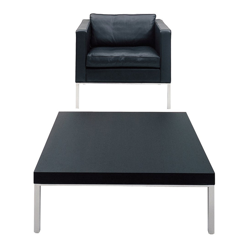 Black leather armchair and sleek black coffee table with silver legs, featuring modern minimalist design.