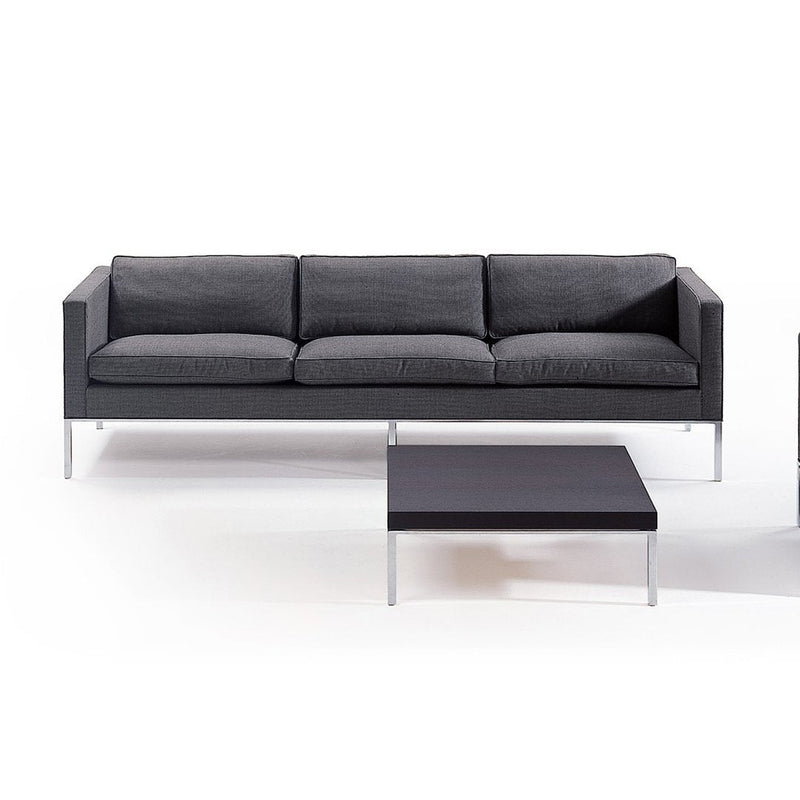 Modern gray sofa with three plush cushions and sleek chrome legs, paired with a minimalist black coffee table.