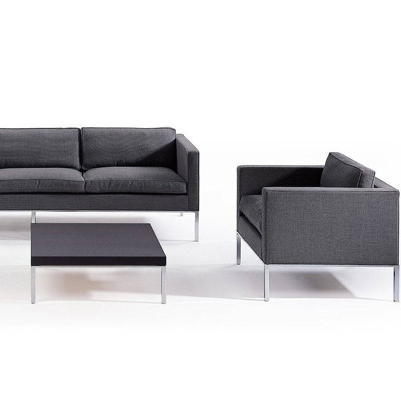 Modern gray sofa and armchair with a sleek black coffee table, featuring a minimalist design and subtle patterns.