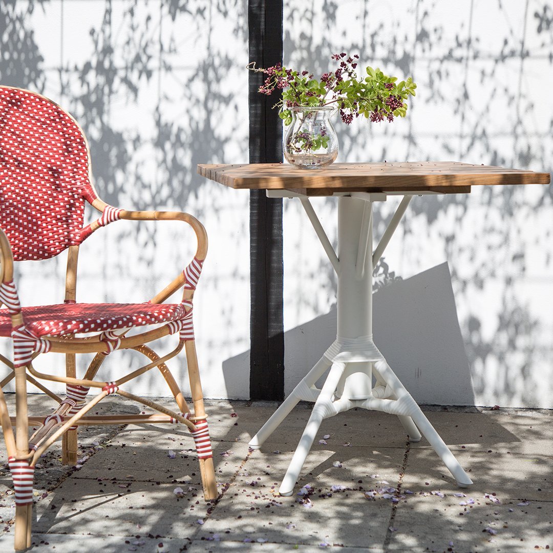 Red and white polka dot chair paired with a natural wood tabletop and white metal base, set against a bright, sunny background.