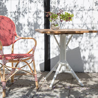 Red and white polka dot chair paired with a natural wood tabletop and white metal base, set against a bright, sunny background.
