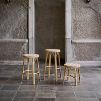 Natural wood bar stools with light woven seats, featuring a simple, elegant design and neutral color tones.