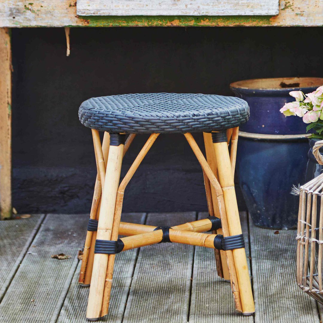 Bamboo stool with a textured black seat and natural wood legs, featuring an elegant woven pattern. Ideal for rustic decor.