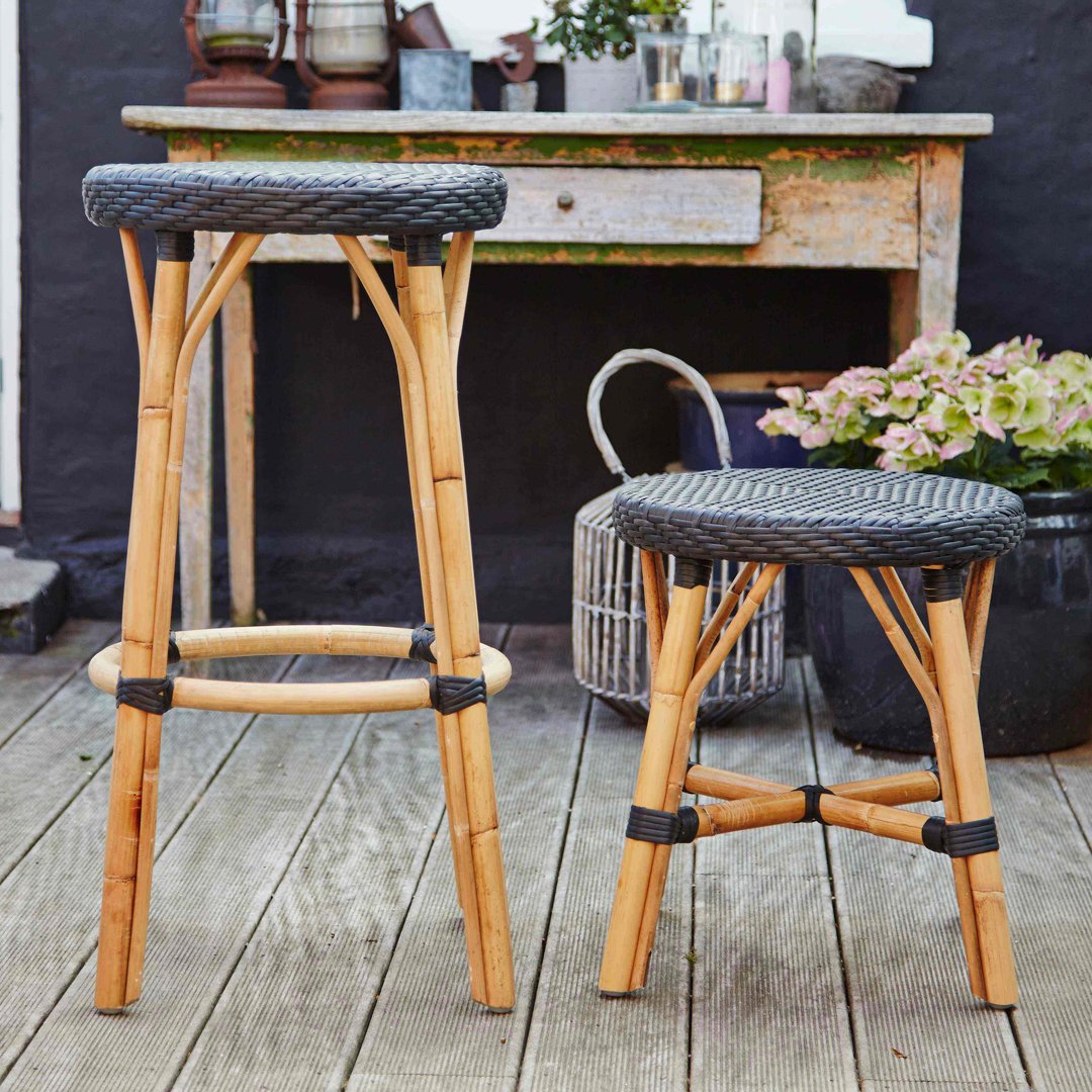 "Natural bamboo stools with black woven seats, showcasing a modern rustic pattern in an outdoor setting."