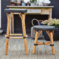 "Natural bamboo stools with black woven seats, showcasing a modern rustic pattern in an outdoor setting."