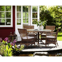 "Four rattan patio chairs with a round table, featuring natural hues and striped cushions, set on a wooden deck."
