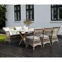 "Neutral wicker patio dining set with soft green cushions against a rustic wood deck."