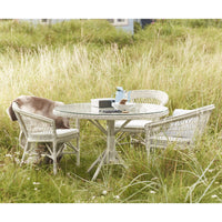 Round patio table and wicker chairs with a light gray finish, complemented by soft, earthy tones and subtle textures.