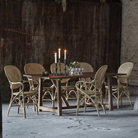 Natural wood dining table with rattan chairs, featuring a warm, earthy color palette and elegant, woven patterns.