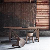 Wooden dining table and stools in earthy tones, featuring natural wood grain patterns against a rustic backdrop.