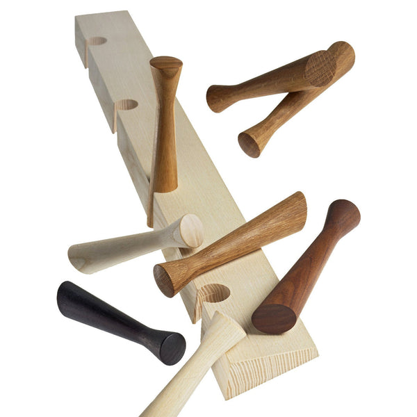 Wooden pegs in natural, light, dark brown, and black hues arranged on a light wood board, showcasing varying shapes and textures.