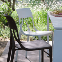 Modern dining chairs in matte white and dark brown, featuring sleek lines and a minimalist design on an outdoor setting.
