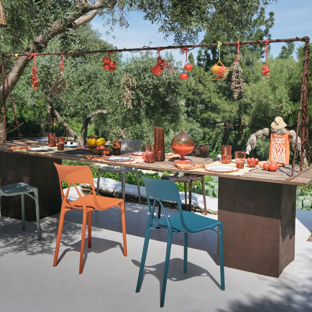 Colorful outdoor dining setup featuring orange and teal chairs, with vibrant reds and earthy tones in decor and tableware.