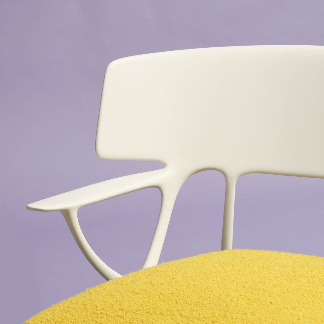 White modern chair with a yellow cushion against a soft purple background, showcasing vibrant colors and clean lines.