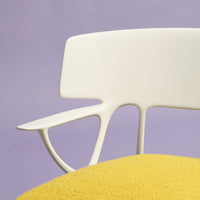 White modern chair with a yellow cushion against a soft purple background, showcasing vibrant colors and clean lines.