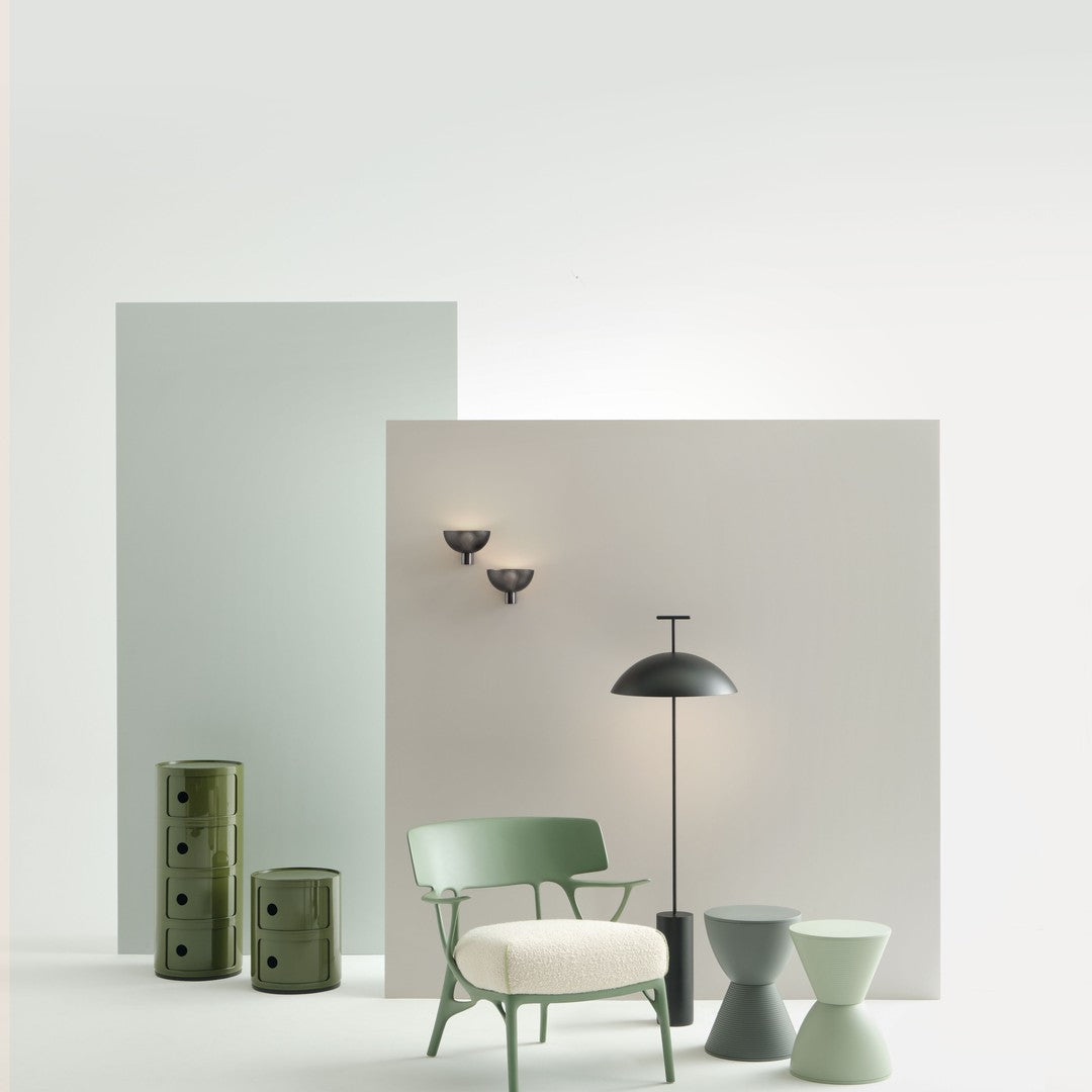 "Pastel green and muted gray backdrop with black lighting fixtures and soft white chair, highlighting modern decor."