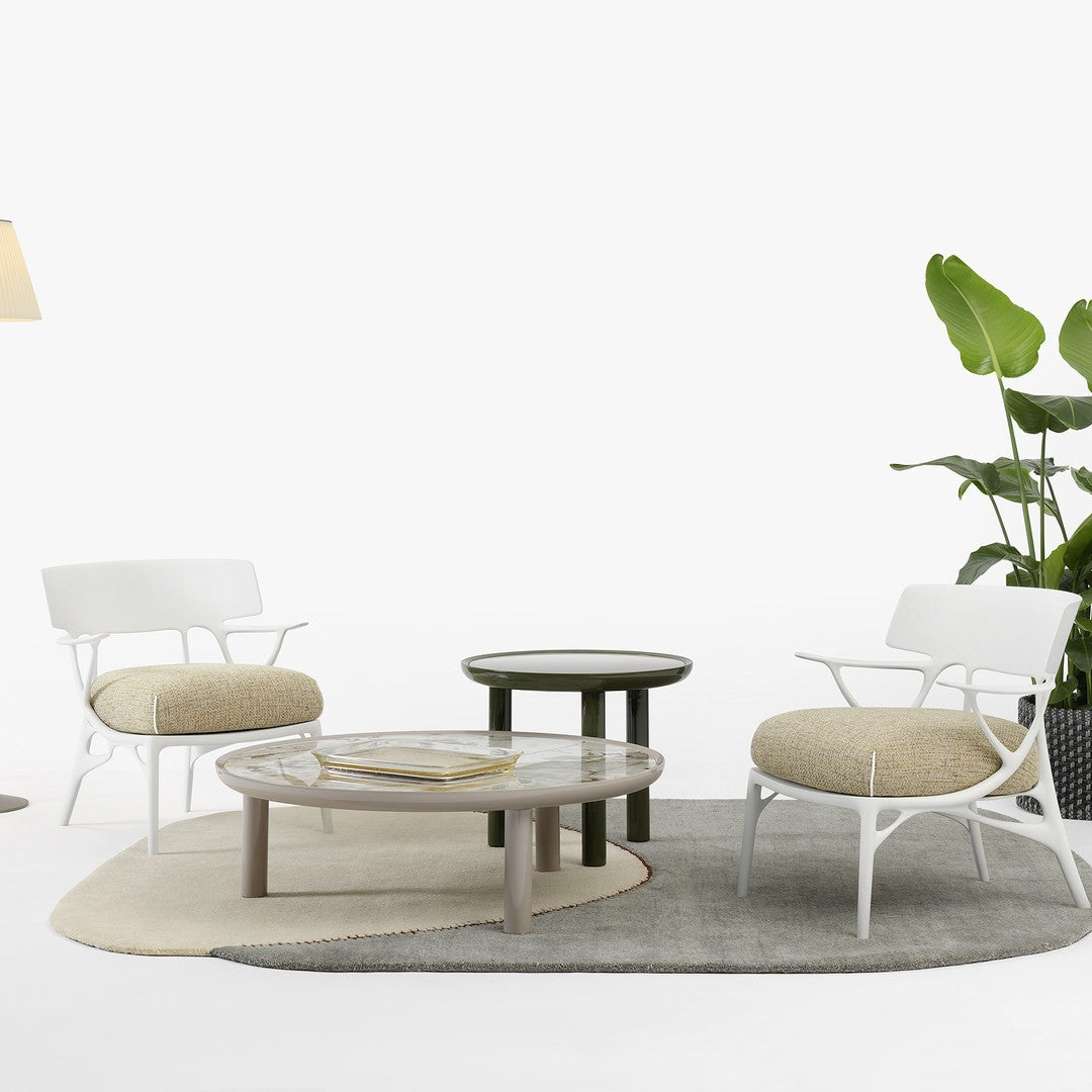White chairs with beige cushions, round gray and green tables on a textured rug. Modern, minimalist style.