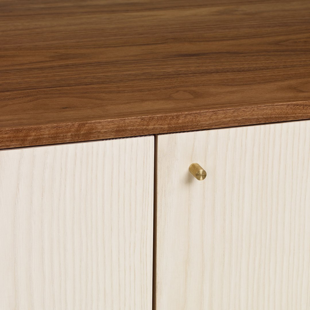 Wooden cabinet with a rich walnut top and light wood grain pattern on doors, featuring a sleek brass knob.