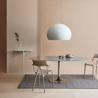 Light beige walls, pastel green pendant light, gray woven rug, and taupe dining chairs create a serene, modern ambiance.