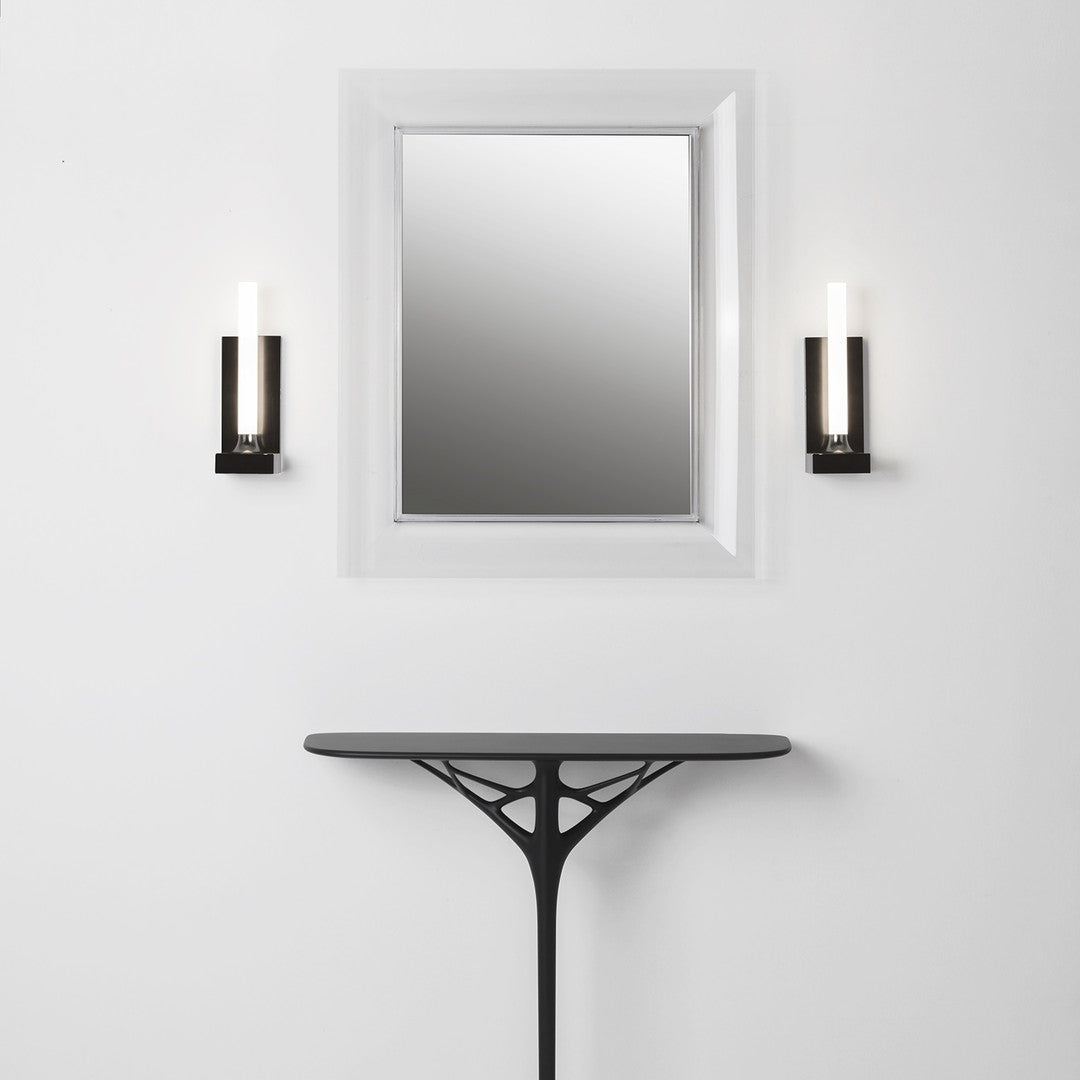 Black sconces with white light beside a sleek black table against a minimalist white wall and mirrored frame.