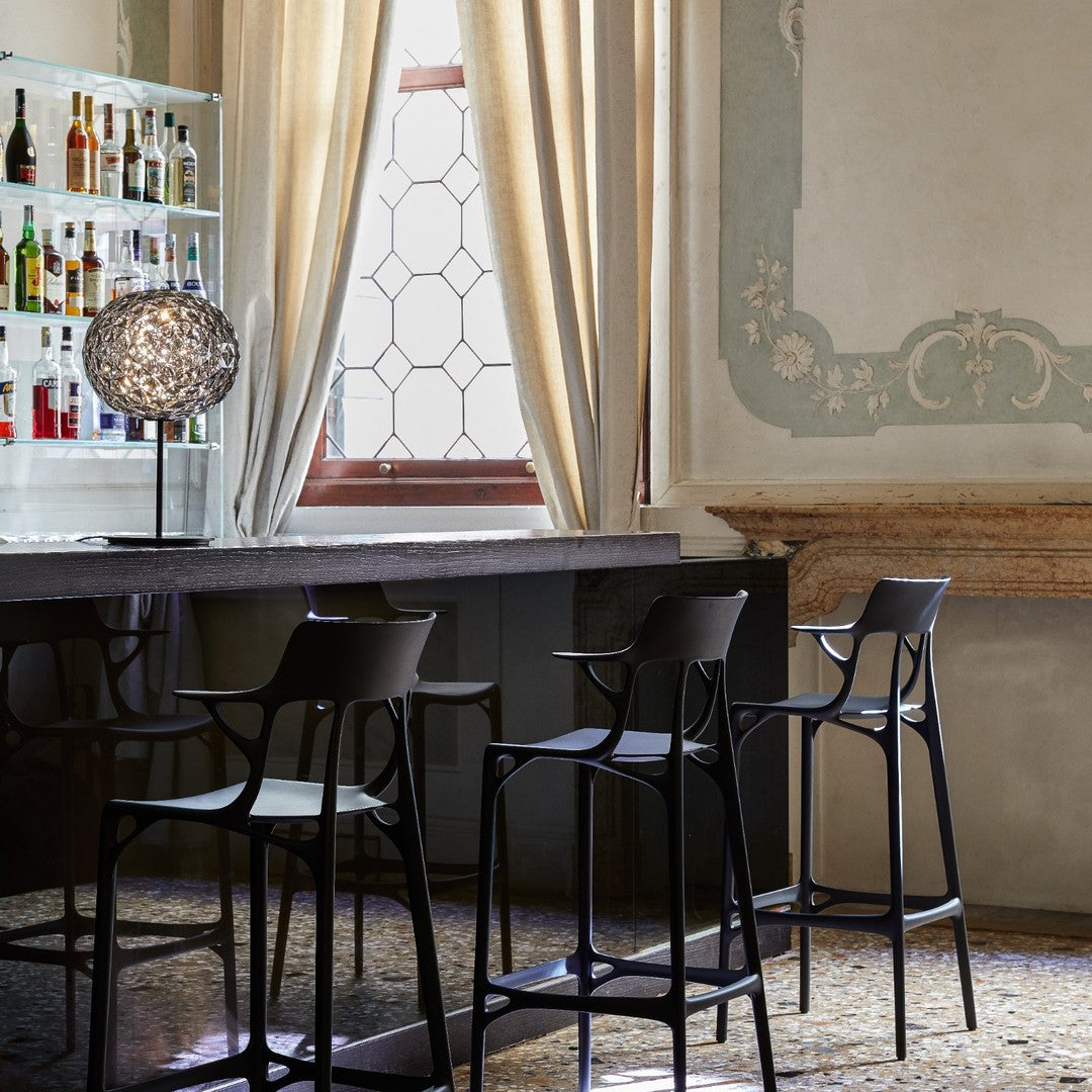 Black bar stools with modern design, set against a light, elegant backdrop featuring muted green and beige accents.
