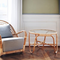 Natural rattan coffee table with glass top, featuring a sleek, minimalist design and earthy tones.