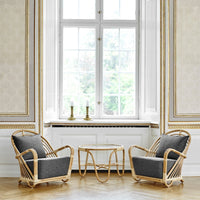 Two gray fabric chairs with natural rattan frames set against a light, elegant interior with muted gold accents.