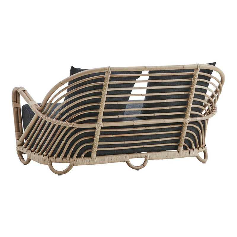 Woven rattan sofa in natural tones with geometric black cushions, combining elegance and modern style.