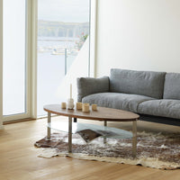 Wooden coffee table with a sleek, modern design, featuring light brown tones and a soft, patterned area rug.