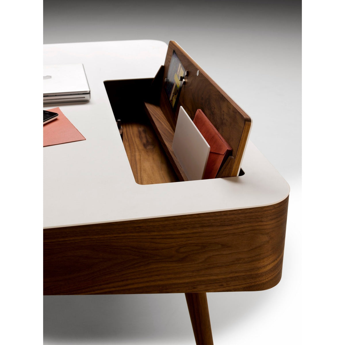 Modern desk featuring a sleek white top and rich walnut wood base with warm, earthy tones and minimalistic design elements.