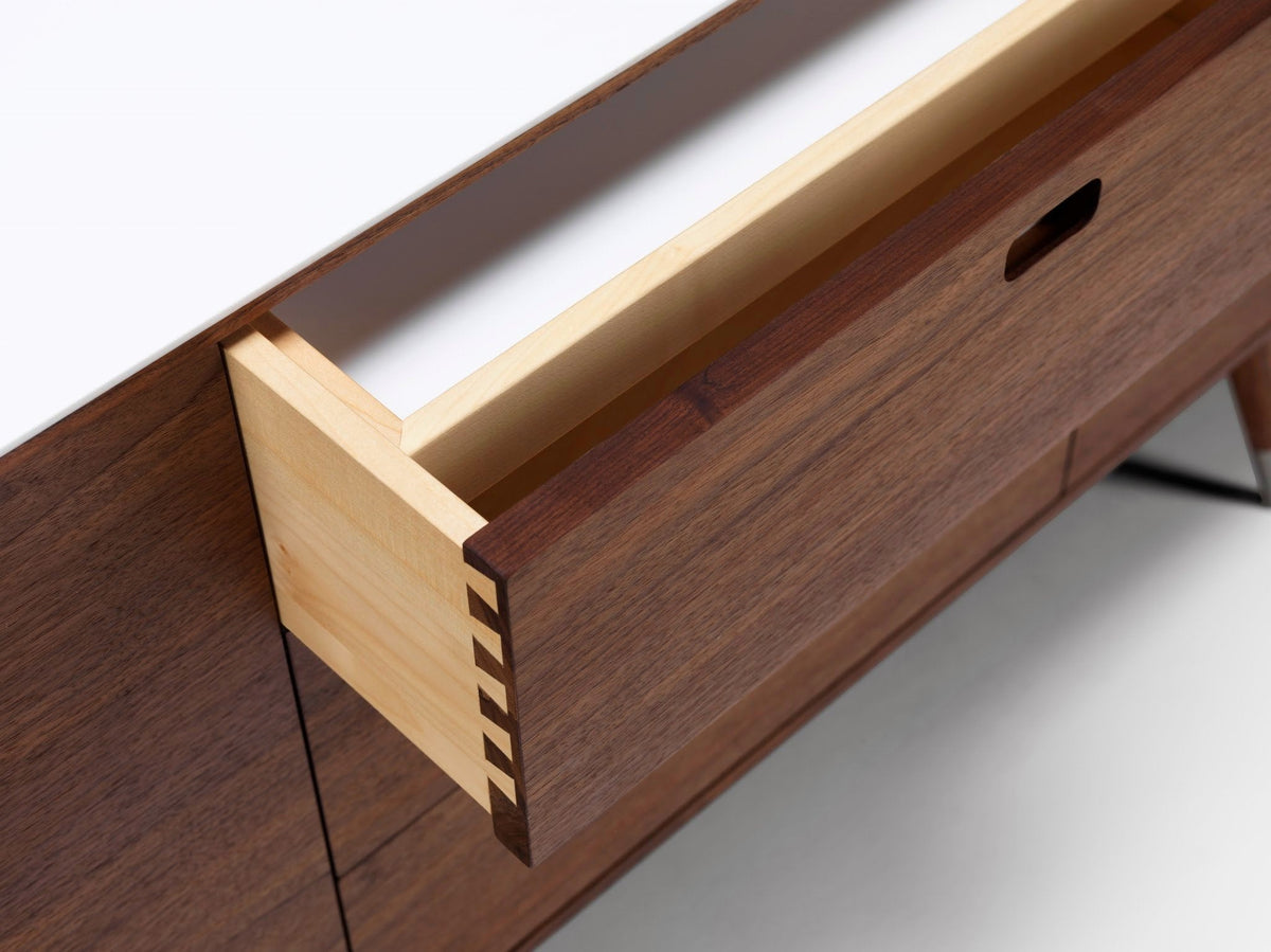 Close-up of a wooden drawer with a light honey finish, contrasting with deep walnut tones and clean white accents.