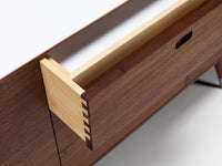 Close-up of a wooden drawer with a light honey finish, contrasting with deep walnut tones and clean white accents.