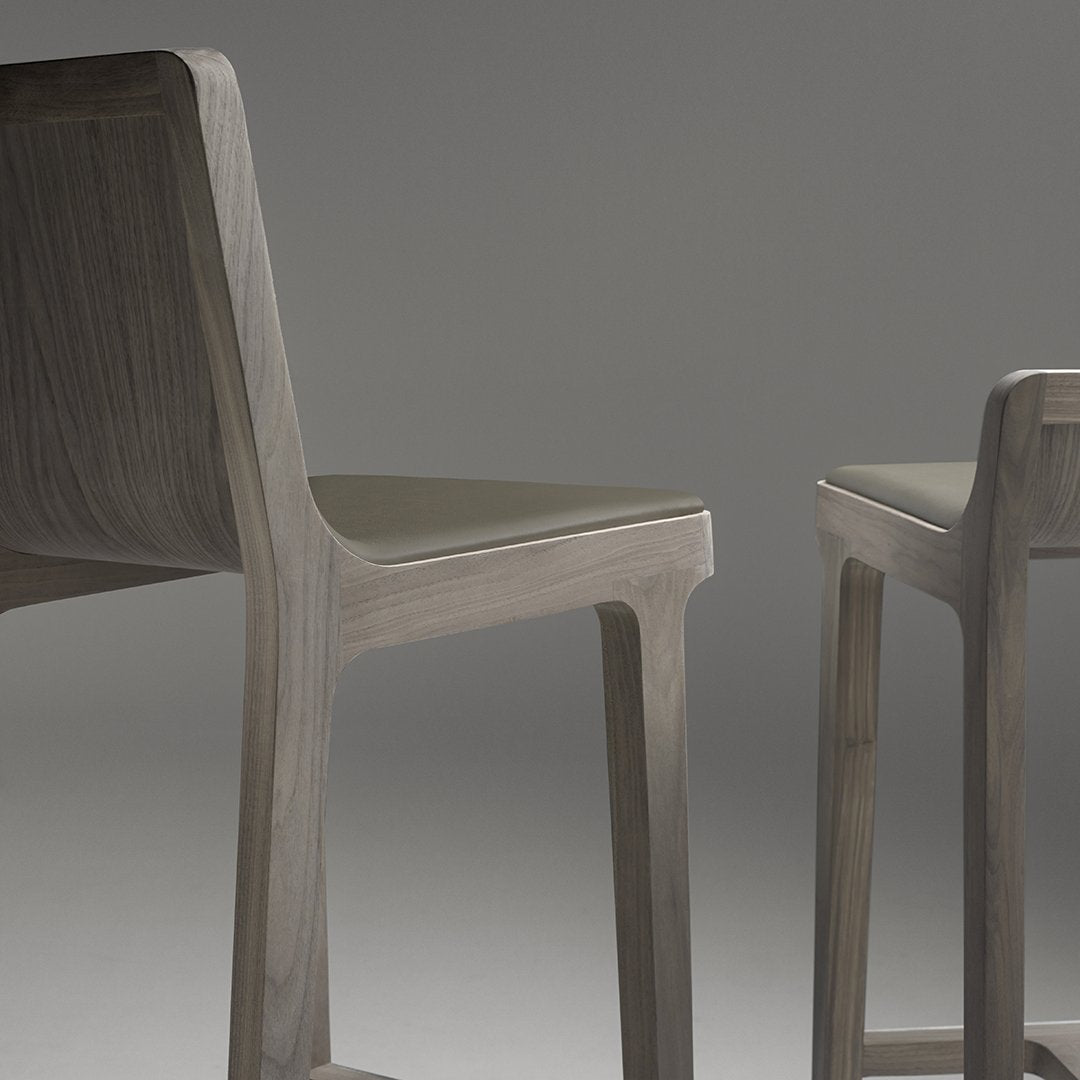 Two minimalist chairs in soft gray wood with subtle grain patterns, featuring sleek, modern lines.
