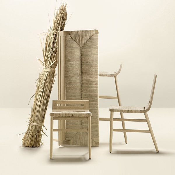 Neutral beige and cream tones with textured woven patterns on minimalist chairs and a decorative backdrop of straw.