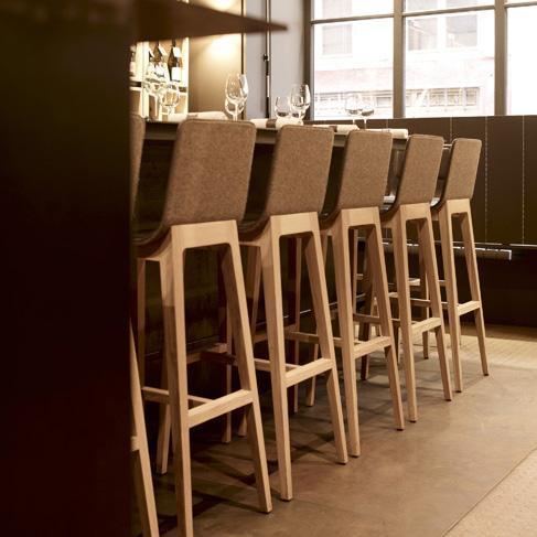 "Neutral-toned bar stools with light wood legs in a modern, minimalist setting, featuring textured fabric upholstery."
