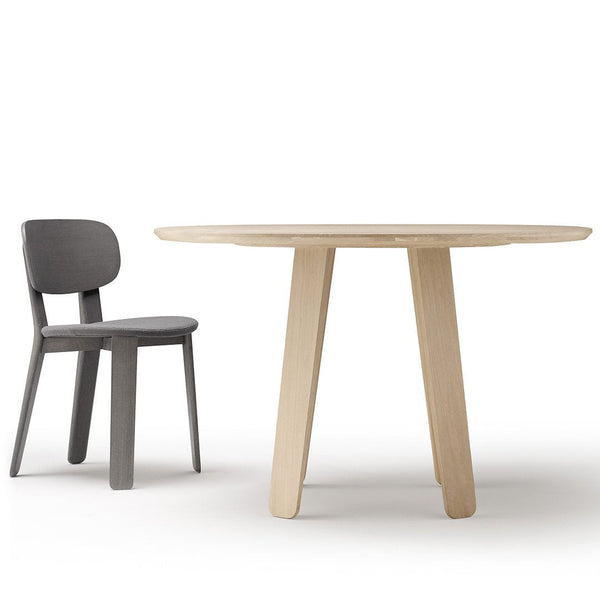 Light wood round table with sleek legs and a modern gray chair, showcasing minimalist design and neutral tones.