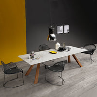 Modern dining table with a white marble top, wooden legs, and sleek black chairs against a yellow and gray backdrop.