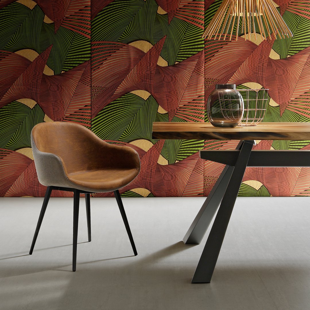 "Stylish chair against vibrant red and green patterned wallpaper with abstract leaf design."