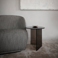 Textured gray fabric sofa beside a sleek black glass side table on a soft beige carpet, creating a modern, sophisticated look.
