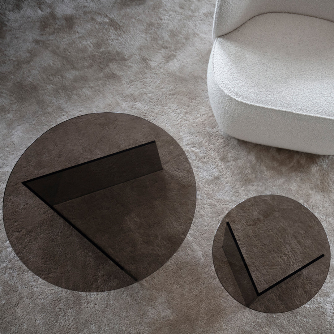 Stylish round and triangular glass coffee tables in dark brown, featuring sleek geometric patterns.