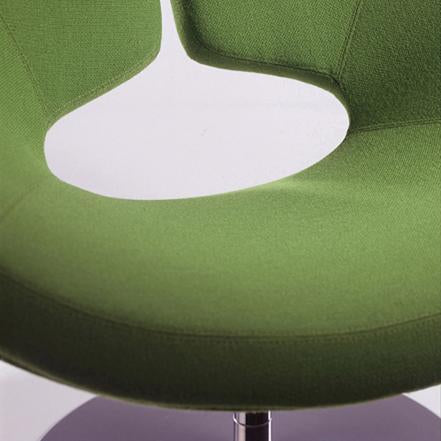 Green upholstered chair with a unique cut-out design, showcasing a smooth texture and modern aesthetic.