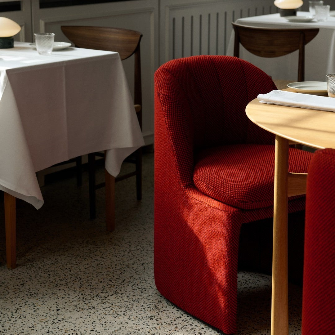 Modern red chair with textured pattern, set against a minimalist dining table and natural light. Stylish interior design.