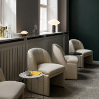 Cream textured chairs against a dark green wall, complemented by a marble table and soft lighting.
