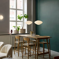 Elegant mint green wall, light wooden table, soft beige upholstery, and sleek white pendant lights create a serene ambiance.