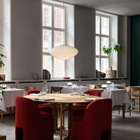 Modern dining room featuring deep red chairs, white table linens, and neutral gray walls with green accents.