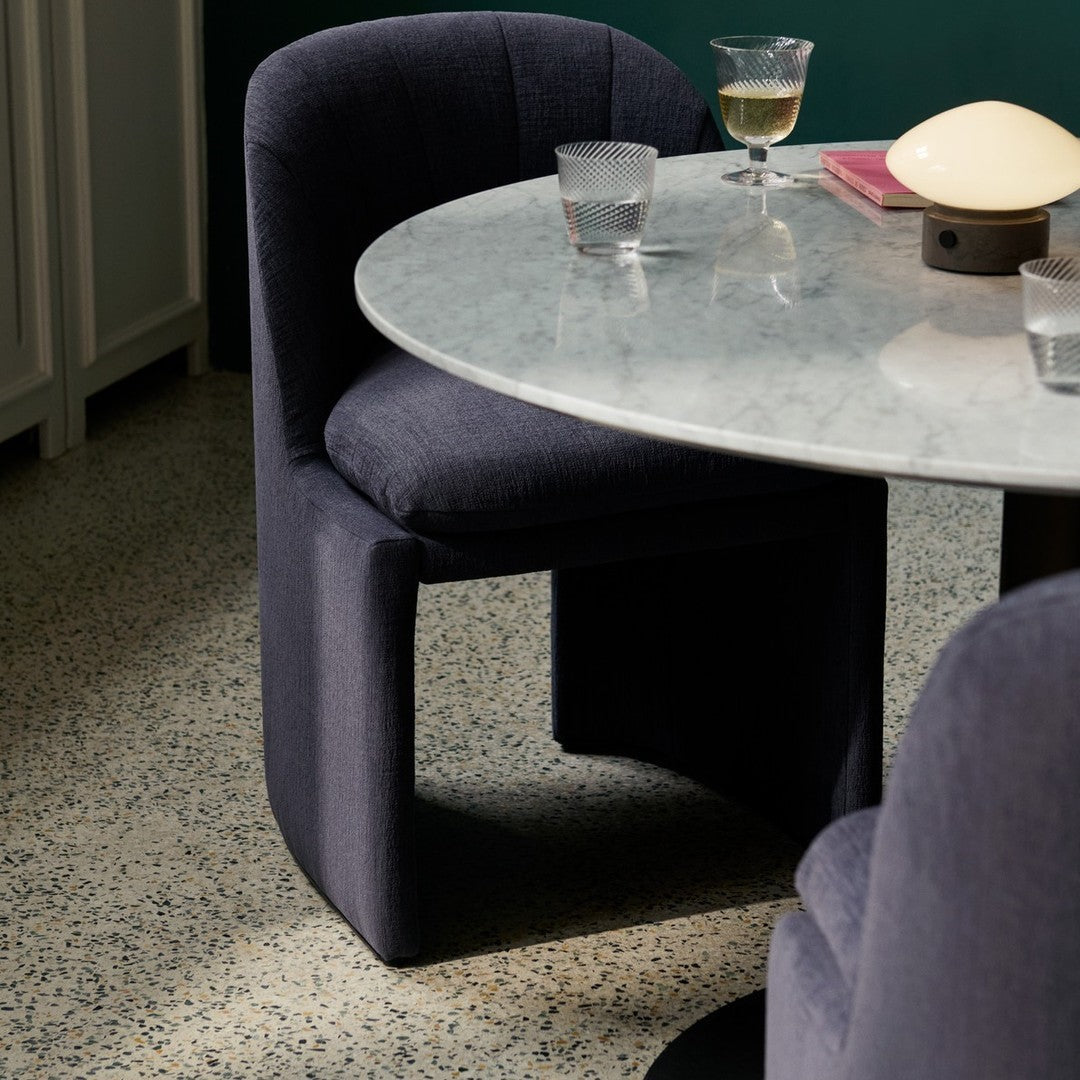 "Stylish navy blue upholstered chair with a marble table and terrazzo floor, creating a modern, sophisticated look."